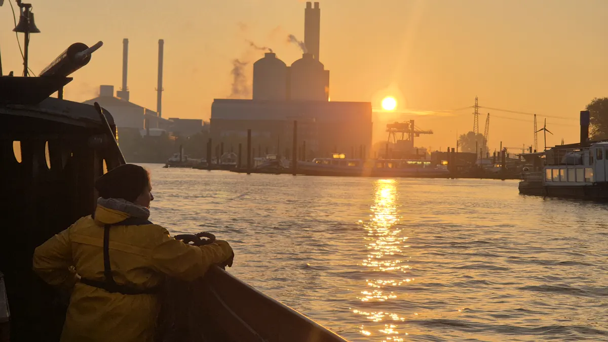 Auszubildender an der Reling bei Sonnenaufgang über dem Hamburger Hafen